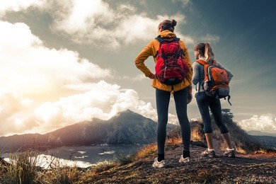 two ladies hikers standing on top of the mountain and enjoying valley view