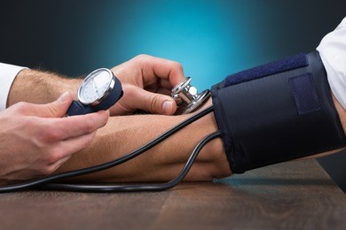 cropped image of male doctor checking blood pressure of patient at table