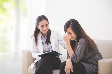 a portrait of an asian female patient consulting with a female doctor, the patient is crying
