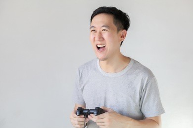 young asian man playing video games - in white isolated background