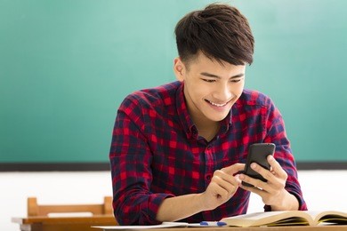 happy student reading smart phone in classroom