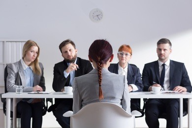 woman during job interview and four elegant members of management