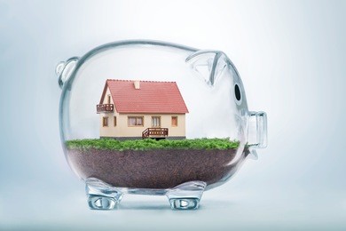 saving to buy a house or home savings concept with model house inside transparent piggy bank