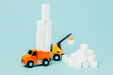 miniature lorry picking huge sugar amount. conceptual image about food industry and sugar. 