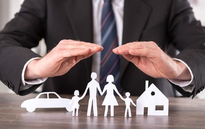 concept of insurance with hands over a house, a car and a family