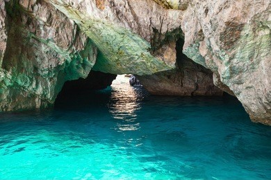 coastal rocks of capri island, small empty grotto with shining sea water inside