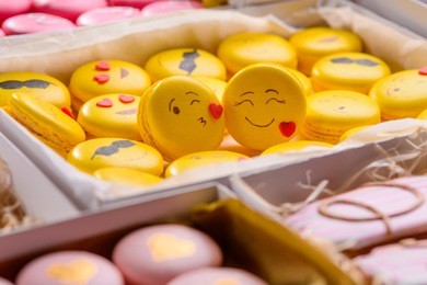 background with sweets in boxes and two yellow macaroon with smiles close-up. the foreground is blurred. a gift on valentine's day.