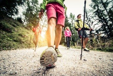 group of hikers with backpacks and sticks walking on a mountain at sunset - four friends making an excursion in the nature