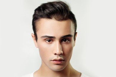 handsome young man portrait. brunette guy in white t-shirt on a light background used, clean skin, studio shot, beauty