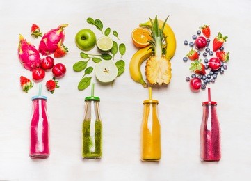 assortment of fruit  and vegetables smoothies in glass bottles with straws on white wooden background. fresh organic smoothie ingredients. superfoods and health or detox  diet food concept.