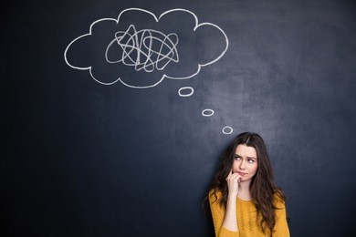 frowning thougthful young woman thinking about problems over blackboard background