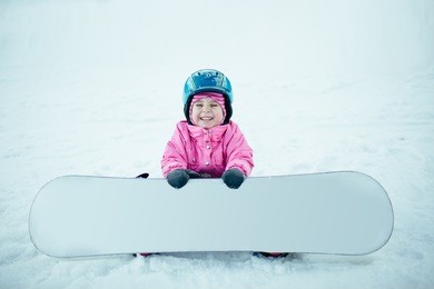 snowboard winter sport. little kid girl playing with snow wearing warm winter clothes.
winter background