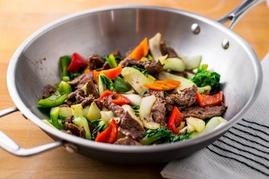 wok stir-fried beef and vegetable on a wooden cutting board.