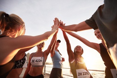 runners high fiving each other after a good training session. group of athletes give each other high five after race.