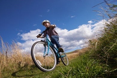 low angle shot of boy riding bike through countryside