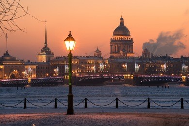 view of the evening city decorated with lights. in the foreground a street light. in the background, the main attractions - the palace bridge and st. isaac sobo. russia, saint-petersburg.