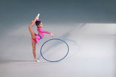 gymnast in a beautiful pink suit doing hoop exercise