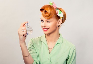 girl with perfume. closeup red head beautiful young woman pretty smiling pinup girl green button shirt holding bottle of perfume and smelling aroma looking at you camera, retro vintage 50's hairstyle