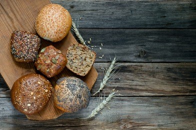assortment of multi-grain bread rolls on on old wooden table