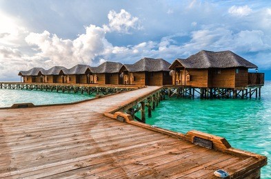 beautiful beach with water bungalows and old wooden pier at maldives