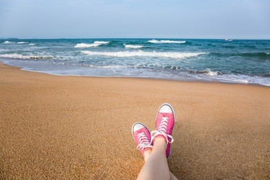 woman sitting on the beach with first person perspective view, legs in focus