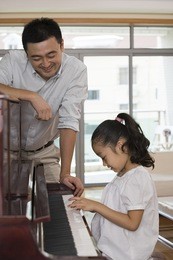 father and daughter playing the piano