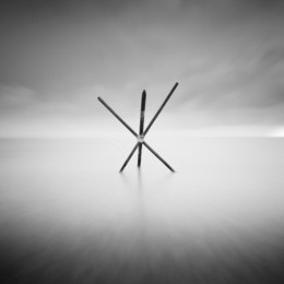 beautiful minimalist black and white seascape with standing wood marker. shot taken in daytime with long exposure