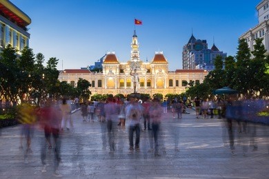 people are walking and taking pictures in front of the city hall building, ho chi minh city, vietnam.
