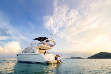 friendship and luxury vacation. two happy young women sitting on the yacht deck looking and pointing away sailing the sea.