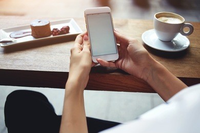 close up of women's hands holding mobile phone with blank copy space screen for your advertising text message or promotional content, female reading news on cell telephone during rest in coffee shop 