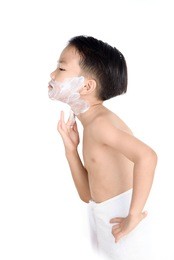 young boy put foam on his face before shaving in the bathroom.