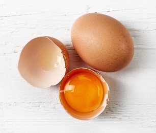 broken eggs on white wooden table, top view