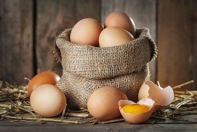 raw organic farm eggs, straw on the old wooden background