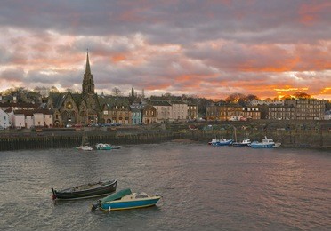 view of leith area of edinburgh, scotland in the winter with red sunset and boats on the foreground