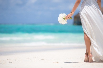 young woman with bouquet of flowers on the beach.