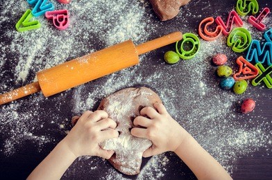 young girl's hands kneading dough. easter baking preparation. close-up of child's hands baking cookies. easter eggs. easter food concept. top view.