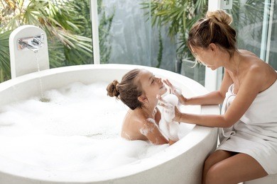 mom washing her child in luxury hotel outdoor bath with a foam, still life
