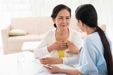 general practitioner and her aged patient talking about heart diseases