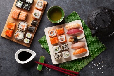 set of sushi and maki roll and green tea on stone table. top view