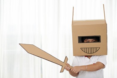 portrait of playful child with cardboard helmet and sword