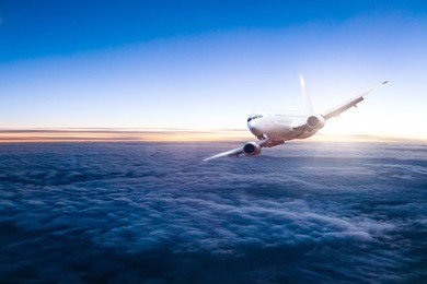 commercial jet aeroplane flying above clouds