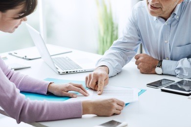 young woman having a business meeting with an executive in his office, he is pointing on a contract and giving explanations