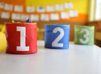 three jars colored red green and blue with written one two and three in the kindergarten classroom