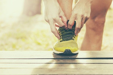 sport, fitness, exercise and lifestyle concept - runner man lacing trainers shoes