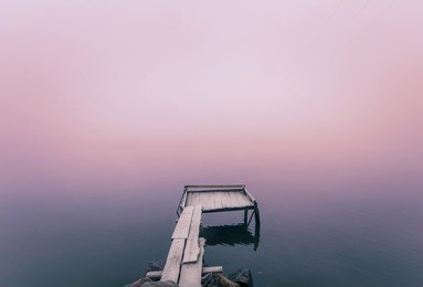 beautiful morning mist by the lake. autumnal fog river walkway. minimalistic long exposure shot.