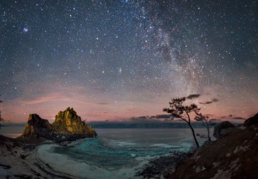 cape burhan (rock shamanka) on olkhon island in the middle of lake baikal on background starry sky and the milky way.