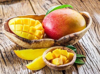 mango fruit and mango cubes on the wooden table.