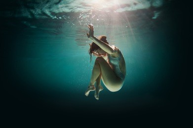 underwater woman portrait in swimming pool at night. dreamlike image.