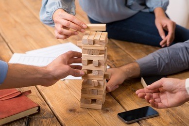 close up of hands helping build a building of wooden pieces. businesspeople planning a new business strategy. business team trying to generate new ideas with wooden bricks. business risk concept.
