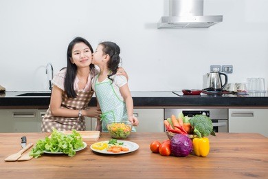 family, children and happy people concept - asian mother and kid daughter cooking in the kitchen at home.
